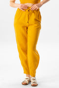 Mustard yellow cotton muslin carrot trousers with elastic waist, drawstring, and tapered ankle legs